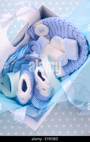 Un garçon de son thème bleu boîte de cadeau de douche de bébé avec des vêtements de bébé, bavoir, bonnet, chaussures, chaussettes et sucette. Banque D'Images