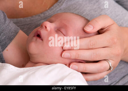 Cropped shot de Naissance bebe Fille endormie dans les bras de son père avec maman en caressant sa tête Banque D'Images
