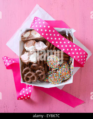 Bonbons au chocolat et biscuits boîte cadeau, recouvert de chocolat avec les guimauves, les bretzels, les bonbons et les cookies sur vintage bois rose tabl Banque D'Images