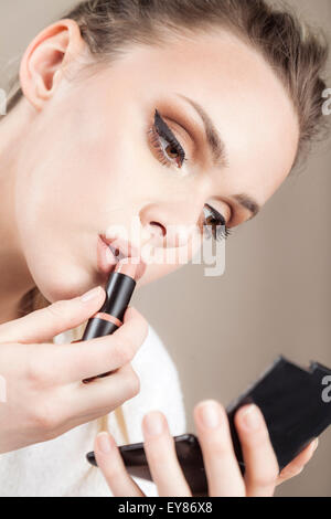 Young woman applying lipstick Banque D'Images