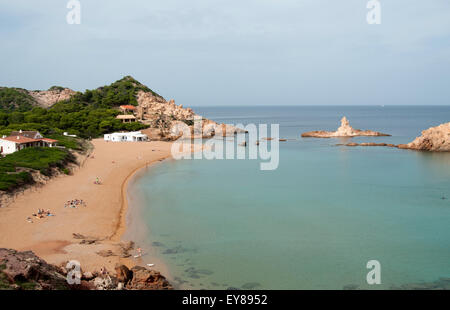 Un peu de touristes le soleil sur la plage de sable de Cala Pregonda sur l'île de Minorque espagne Banque D'Images