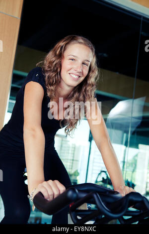 Happy blonde woman on a spinning bike Banque D'Images