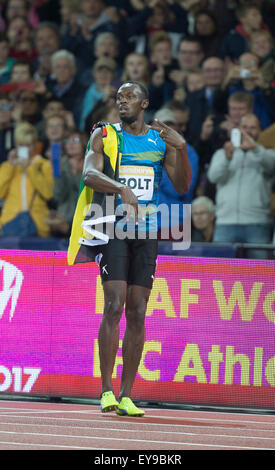 Queen Elizabeth Olympic Park, Londres, UK. 24 juillet, 2015. Sainsburys Anniversaire Jeux. Usain Bolt (JAM) célèbre avec le drapeau jamaïcain par-dessus son épaule après sa victoire dans la finale du 100 m hommes. Credit : Action Plus Sport/Alamy Live News Banque D'Images