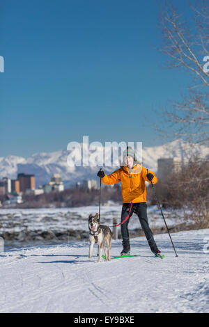 Une jeune femme Skijors avec son chien de traîneau Husky Alaska Le Tony Knowles Coastal Trail, Anchorage, Southcentral Alaska, USA. Banque D'Images