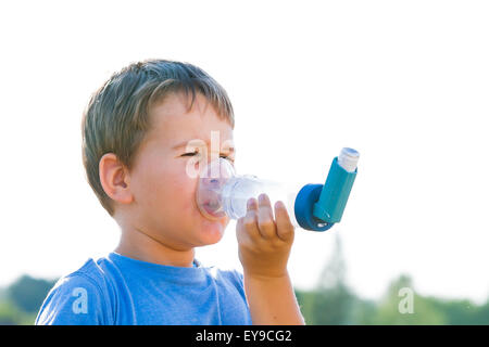 Garçon à l'aide d'inhalateur pour l'asthme au village avec le coucher du soleil d'été Banque D'Images