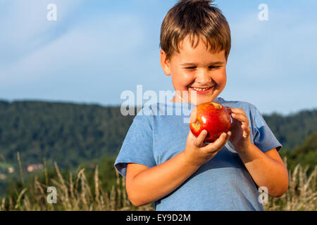 Garçon avec une pomme rouge dans la nature Banque D'Images