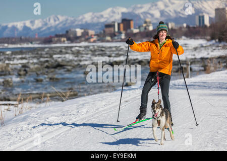 Une jeune femme skijors avec son chien de traîneau Husky Alaska le Tony Knowles Coastal Trail, Anchorage, Southcentral Alaska, USA. Banque D'Images