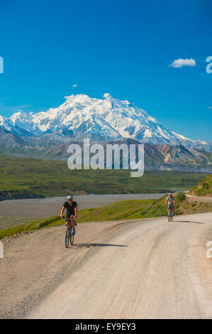 Deux hommes la bicyclette sur la route du parc avec Mt. McKinley dans l'arrière-plan, l'intérieur de l'Alaska, l'été Banque D'Images