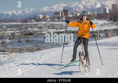 Une jeune femme skijors avec son chien de traîneau Husky Alaska le Tony Knowles Coastal Trail, Anchorage, Southcentral Alaska, USA. Banque D'Images