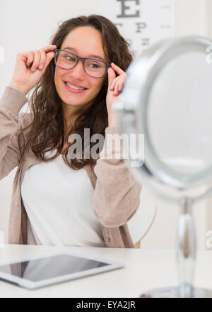 Vue d'une jeune femme séduisante à essayer de nouvelles lunettes Banque D'Images