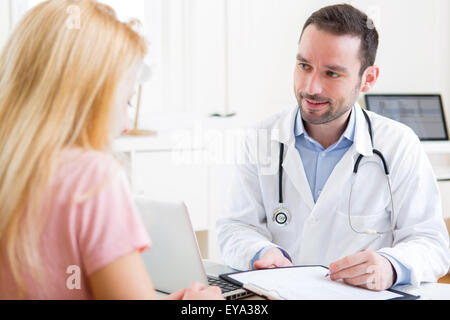 Vue d'un jeune médecin attrayant tout en parlant du patient de prendre des notes Banque D'Images