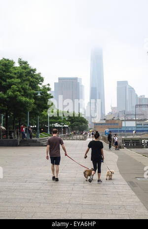Couple promènent leurs chiens, jogging à Hudson River Park. La tour de la liberté, Manhattan en arrière-plan. NYC. USA. Banque D'Images