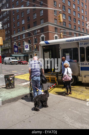 Mobilité plus homme avec chien entre dans les transports spéciaux, camion, bus, la ville de New York, Manhattan, USA. Banque D'Images