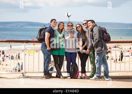Bournemouth, Dorset, UK 25 juillet 2015. Groupe de jeunes gens debout sur la jetée de Bournemouth en tenant une au bord de la mer, selfies à l'aide de bâton selfies en juillet Crédit : Carolyn Jenkins/Alamy Live News Banque D'Images
