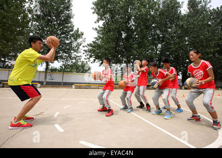 Shanghai, Chine, Anhui Province. 24 juillet, 2015. Un étudiant (L) de l'Université normale de Beijing à gauche derrière les enfants enseigne comment passer des balles dans un match de basket-ball dans Mengcheng Comté de Linyi City, est de la Chine, la Province de l'Anhui, le 24 juillet 2015. Enfants dans différentes régions de la Chine ont passé leurs vacances d'été de diverses façons. 2 Rong Ye Street © Hu/Xinhua/Alamy Live News Banque D'Images