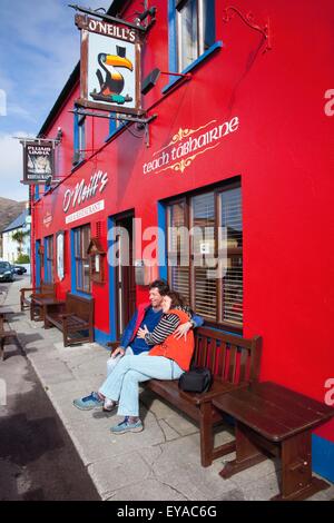 Un couple est assis sur un banc à l'extérieur O'Neill's Pub ; Allihies, comté de Cork, Irlande Banque D'Images