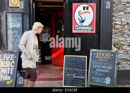 Femme lisant Tableau Affichage à l'extérieur ; Pub Killarney, comté de Kerry, Irlande Banque D'Images