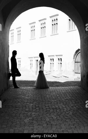 Newlywed couple regardant fixement l'un l'autre dans un couloir. Image en noir et blanc avec du grain ajouté comme effet. Banque D'Images