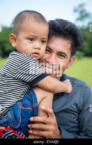 SIEM REAP, Cambodge - 30 octobre 2014 : jeune père détient son fils debout devant de verdure tropicale à Angkor Wat. Banque D'Images