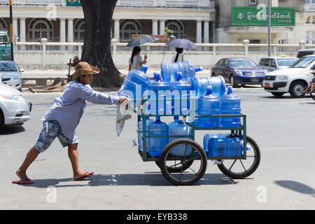 Yangon, Myanmar-May 8e 2014 : un homme pousse un chariot chargé avec des bouteilles d'eau. Les livraisons sont toujours effectuées de cette façon. Banque D'Images