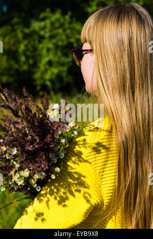 Fille de fils de bouquet de fleurs sauvages on meadow Banque D'Images