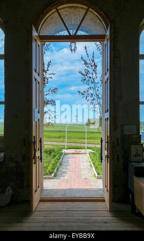 Vue sur un paysage rural à travers les portes ouvertes de l'église orthodoxe. Passage du temple à travers le passage de fer avec cress Banque D'Images