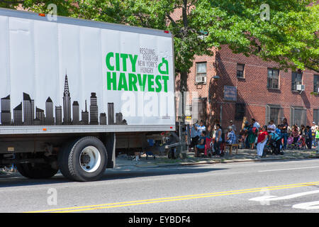 Les gens à attendre en ligne gratuitement la nourriture distribuée par ville la récolte, pour les affamés, à Hamilton Heights à New York. Banque D'Images