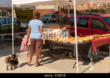 Une femme avec son chien porte sur les produits de boulangerie au Sugar Hill Greenmarket à New York City. Banque D'Images