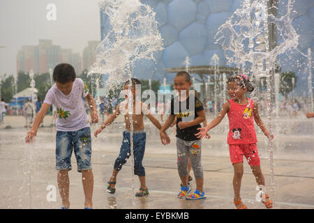 Les enfants s'amusant à jouer parmi les têtes d'eau devant le Cube d'eau au Parc olympique de Beijing - Juillet 2015 Banque D'Images