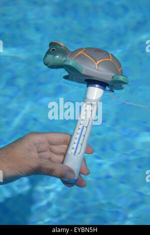 La mesure de la température de l'eau à 31c dans une piscine avec un thermomètre aquatique en Espagne pendant une vague. Banque D'Images