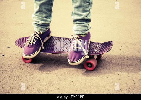 Adolescent pieds de jeans et gumshoes sur une planche à roulettes, photo avec correction tonale rétro, old style Banque D'Images