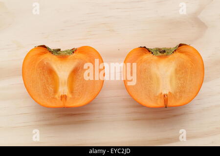 Une couleur orange kaki coupé en deux sur une planche en bois Banque D'Images