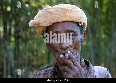 Homme avec une coiffure locale ancienne fumer un cigare, portrait, Indein, lac Inle, l'État de Shan, Myanmar Banque D'Images