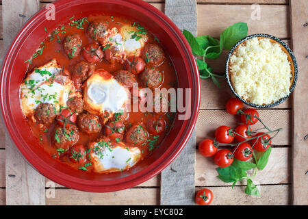 Tajine marocain d'agneau kefta (boulettes), de tomates et d'œufs sur une table en bois, selective focus Banque D'Images