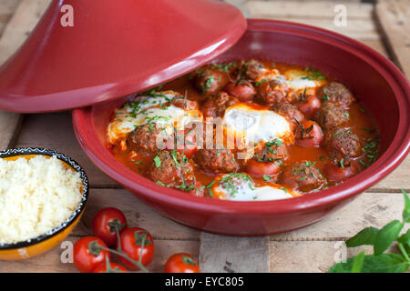 Tajine marocain d'agneau kefta (boulettes), de tomates et d'œufs sur une table en bois, selective focus Banque D'Images