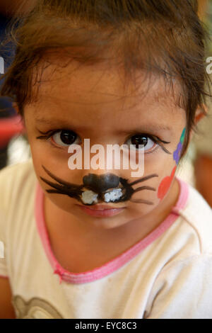 Fille avec visage peint comme un chat à un festival des enfants, initiative de paix de la police et de l'Église catholique dans le bidonville de Banque D'Images