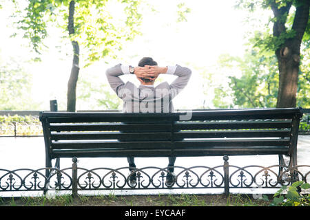 Vue arrière portrait d'un homme d'affaires reposant sur le banc à l'extérieur Banque D'Images