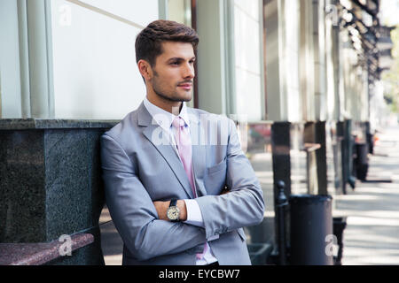 Portrait d'une pensive businessman with arms folded debout à l'extérieur dans la ville Banque D'Images