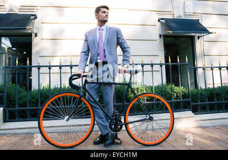 Portrait of a handsome businessman standing with bicycle outdoors Banque D'Images