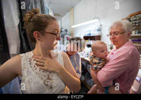 Broomfield, Colorado - une jeune femme est équipé d'une robe de mariage alors que sa mère tient son bébé. Banque D'Images