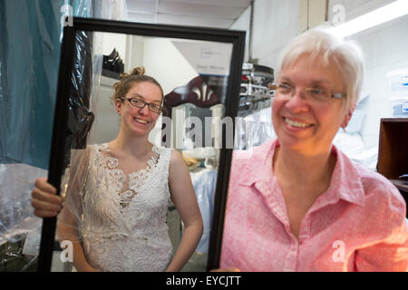 Broomfield, Colorado - une jeune femme essaie sur sa robe de mariage non fini comme sa mère montres. Banque D'Images