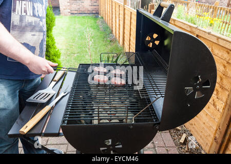 Barbecue à la maison. Man barbecuing hamburgers sur un barbecue dans le jardin Banque D'Images