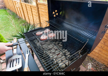 Un barbecue à la maison. Personne seulement mettre les galettes sur le barbecue dans le jardin Banque D'Images