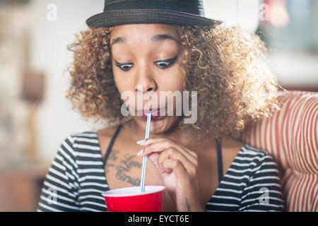 Portrait de jeune femme tirant un visage tout en boivent des boissons Banque D'Images