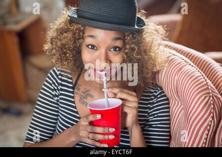 Portrait of young woman wearing fedora et boivent des boissons Banque D'Images