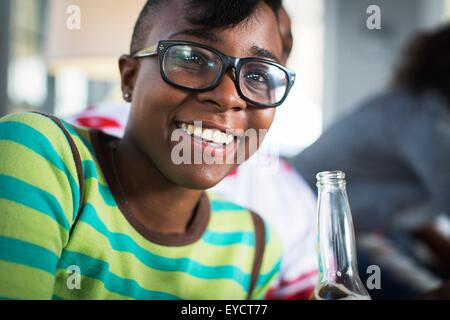 Jeune femme à boire la bière en bouteille sur salon canapé Banque D'Images