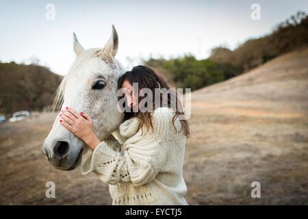 Young woman leaning against et un cheval blanc dans la zone Banque D'Images