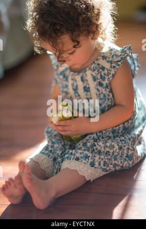 Jeune fille, assise sur le plancher, Playing with toy Banque D'Images