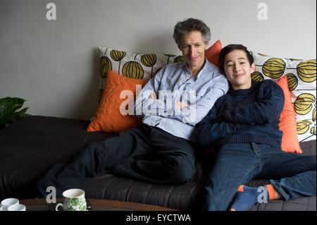 Portrait de père et fils adolescent relaxing on sofa Banque D'Images