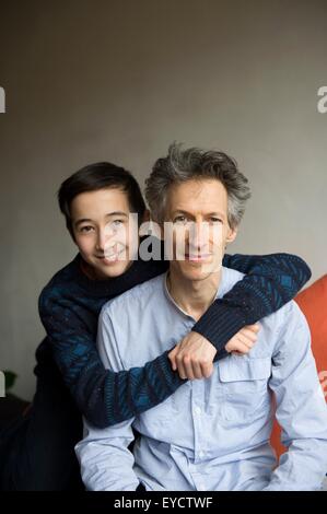 Portrait of teenage boy avec bras autour de père sur canapé Banque D'Images